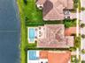 Waterfront property featuring a paver patio, a custom swimming pool with an integrated spa, and a tiled roof