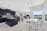 Kitchen featuring dark cabinetry, center island with stone-finish countertop, tiled flooring, stacked stone wall accents, and oversized windows