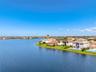 Waterfront property featuring a tile roof, manicured lawn, and perimeter fencing