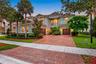 Two-story residence featuring a tile roof, stucco exterior, paver driveway, attached two-car garage, and second-story balcony with decorative metal ra