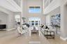 Grand foyer featuring soaring double-height ceilings, large-format tile flooring, a multi-story glass window configuration, arched architectural openi
