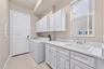 Laundry area featuring white cabinetry, a built-in drop-in sink, solid-surface countertops, and tile flooring