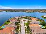 Waterfront property featuring tile roofing, concrete paved cul-de-sac, and landscaped palm trees