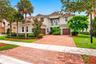Two-story residence featuring a tile roof, stucco exterior, paver driveway, two-car garage, and a second-story iron railed balcony