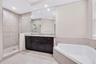 Bathroom featuring a dark wood vanity with a stone countertop, an oversized wall mirror, a corner jetted soaking tub, and a glass-enclosed walk-in sho