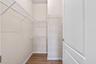 Walk-in storage space featuring wood-finish flooring, multi-level wire shelving, and an integrated vertical wire rack