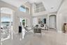Double-height ceilings, large-format tile flooring, arched architectural detailing, sliding glass doors, and a decorative mezzanine railing