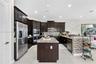 Kitchen featuring dark cabinetry, stone-surface countertops, central island, stainless steel appliances, and large-format tile flooring