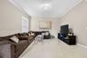 Spacious room featuring neutral wall tones, large-format tile flooring, crown molding, and a central ceiling-mounted light fixture
