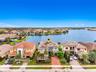 Waterfront property featuring a multi-story exterior with a tile roof, paved driveway, and mature landscaping
