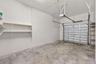 Attached garage featuring concrete flooring, a paneled overhead door, an automated ceiling-mounted door opener, and fixed wall-mounted shelving