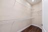 Storage space featuring multi-level white wire shelving and dark wood-finish flooring