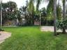 Expansive backyard featuring a natural stone patio, sand sports court, mature landscaping, and wood privacy fencing