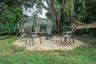 Gravel fire pit area bordered by pressure-treated timber, mature shade trees, and mature landscaping