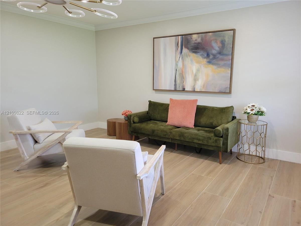 Light-toned wood-finish flooring, neutral wall palette, crown molding, and a contemporary multi-ring flush-mount ceiling fixture
