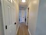 Hallway featuring wood-finish flooring, crown molding, multi-panel doors with matte black hardware, and a louvered closet door