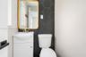 Wall-mounted sink with brushed nickel faucet, matte black hexagonal tile accent wall, and integrated cabinetry