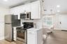 Kitchen featuring white shaker-style cabinetry, stainless steel appliances, stone-look countertops, and wood-finish flooring