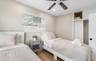 Neutral-toned room featuring wood-finish flooring, a ceiling fan with integrated lighting, a window with horizontal blinds, and a built-in closet with