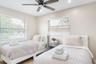 Neutral-toned room featuring dual windows with horizontal blinds, wood-finish flooring, and a ceiling fan with integrated lighting