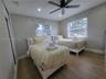 Bedroom featuring wood-finish flooring, recessed lighting, a ceiling fan, dual windows, and closet storage with louvered doors