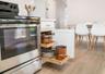 Kitchen featuring stainless steel range, custom white cabinetry with pull-out shelving, and wood-finish flooring