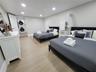 Neutral-toned interior space featuring light wood-finish flooring, recessed lighting, and a dedicated laundry area with stacked washer and dryer unit