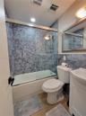 Bathroom featuring a shower-tub combination with sliding glass doors, hexagon-patterned tile surround, vanity with an integrated basin, and framed wal
