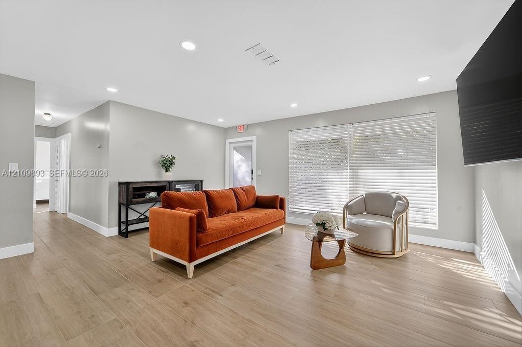 Interior living space featuring wood-finish flooring, recessed lighting, and large windows with horizontal blinds