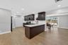 Kitchen featuring dark wood cabinetry, quartz countertops, a breakfast bar, recessed lighting, and wood-finish flooring