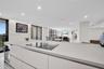 Sleek kitchen featuring flat-panel cabinetry, light-toned stone-surface countertops, built-in stainless steel double wall ovens, a built-in microwave,