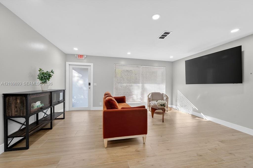 Neutral-toned interior featuring wood-finish flooring, recessed lighting, and a single-pane glass door with white trim