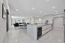 Open kitchen featuring matte-finish cabinetry, a large central island with a solid-surface countertop, integrated cooktop, polished tile flooring, and