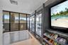Polished white flooring featuring dark linear patterns, glass partition railing, circular pendant lighting, and a dark accent wall