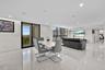 Open-concept interior featuring large-format tile flooring, floor-to-ceiling windows, recessed lighting, and a sliding glass door to an exterior balco