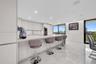 Modern kitchen featuring a large central island with light-toned stone surfaces, integrated wine cooler, minimalist handleless cabinetry, and polished