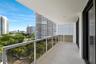 Large-format tile flooring, recessed ceiling lighting, sliding glass door with balcony access, and built-in wall shelving
