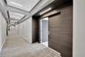 Hallway featuring recessed tray ceiling lighting, wood-finish wall paneling, and neutral carpeting