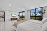 Covered balcony featuring tile flooring and a glass railing with metal framing, overlooking coastal foliage and water