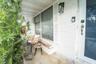 Covered front porch featuring white painted brick exterior, built-in masonry planter, shutter accents, and wall-mounted lantern lighting