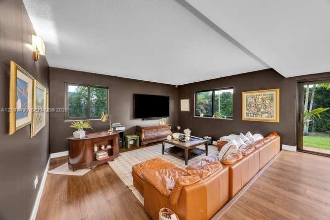Spacious room featuring wood-finish flooring, two large sliding glass doors, dual windows, and wall-mounted lighting