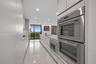 Open kitchen featuring flat-panel cabinetry, light-toned waterfall countertop, built-in wine refrigeration, large-format tile flooring, and floor-to-c