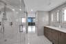 Primary Bathroom featuring large-format tile wall cladding, a double vanity with stone countertop, frameless glass shower enclosure with rainfall show