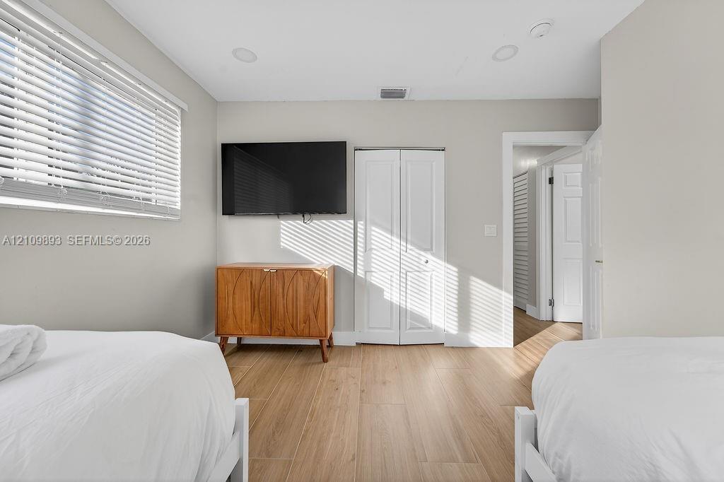 Room featuring wood-finish flooring, white bi-fold closet doors, recessed lighting, and horizontal window blinds
