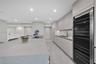Kitchen island featuring a flat-panel cabinetry base, integrated under-counter beverage refrigerator, and an inset electric cooktop with a neutral-ton