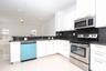 Kitchen featuring white cabinetry, dark stone countertops, stainless steel appliances, and large-format tile flooring