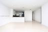 Open-concept interior featuring large-format tile flooring, recessed ceiling lighting, and a breakfast bar with high-gloss cabinetry