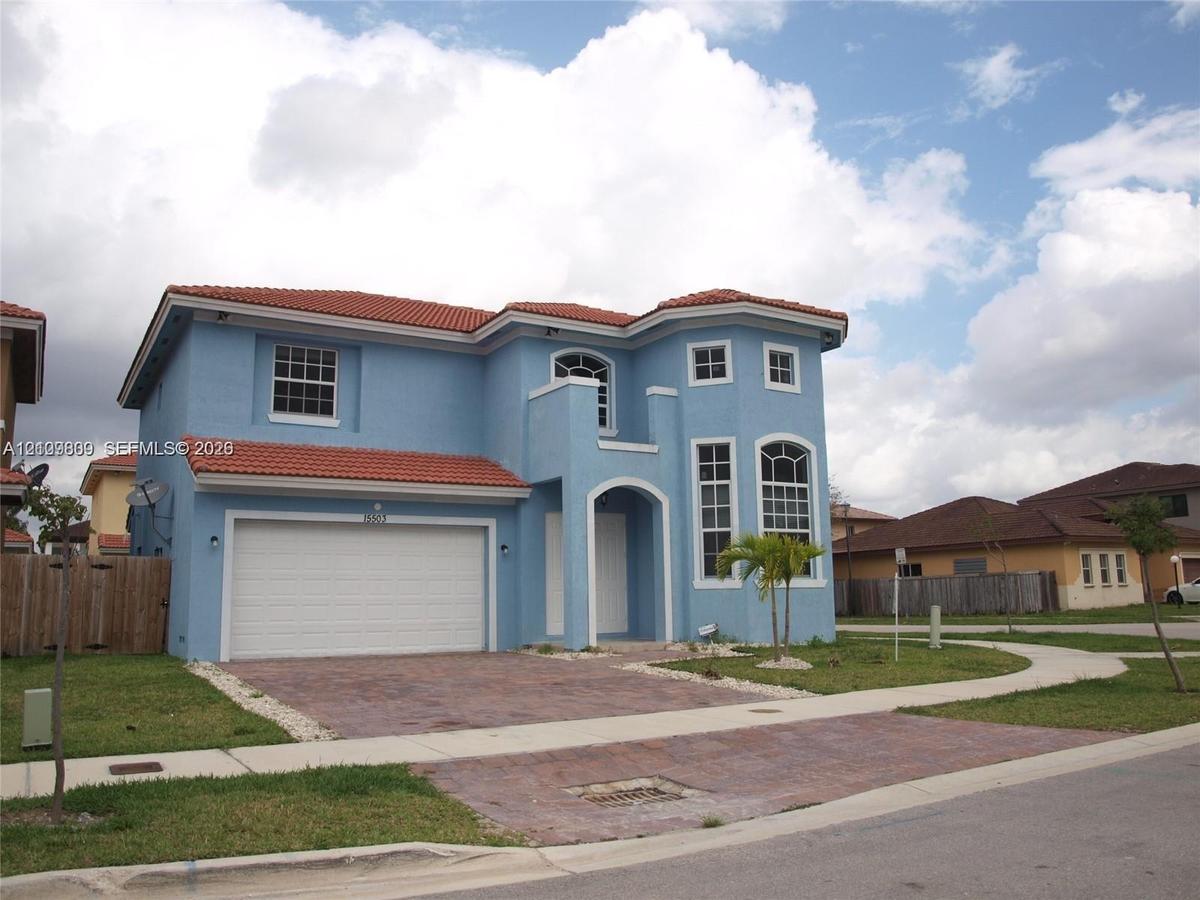 Two-story exterior featuring a clay tile roof, arched windows, and a paved stone driveway