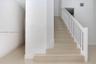 Staircase featuring tile treads and a white wooden handrail with vertical balusters