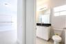 Bathroom featuring a vanity with dark stone countertop, rectangular undermount sink, wall-spanning mirror, multi-bulb vanity light, and polished tile 